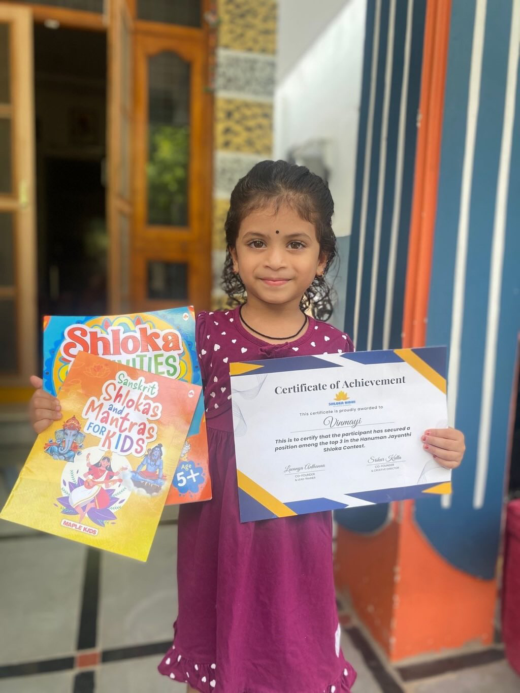 Vinmayi, first place winner of Shloka Nidhi shloka contest, receiving certificate and shloka books